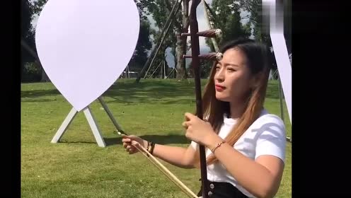 美女坐在草地上拉二胡,这首曲子很欢快,听着莫名想抖腿