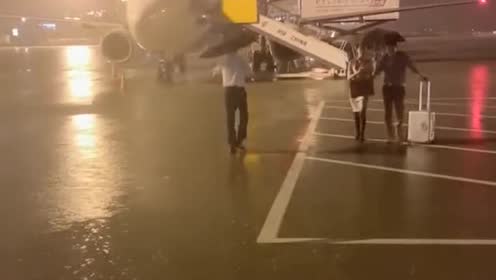 空姐空少用雨伞把乘客送上摆渡车!衣服都淋湿了