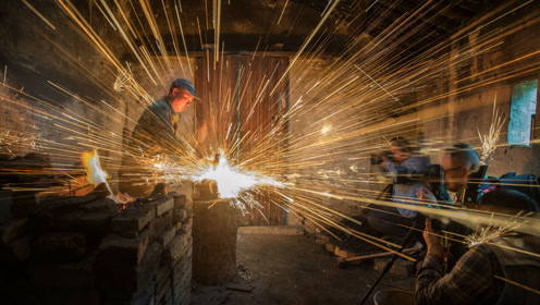 帅哥身穿迷彩服手拉风箱打铁 再现农耕时代老手艺